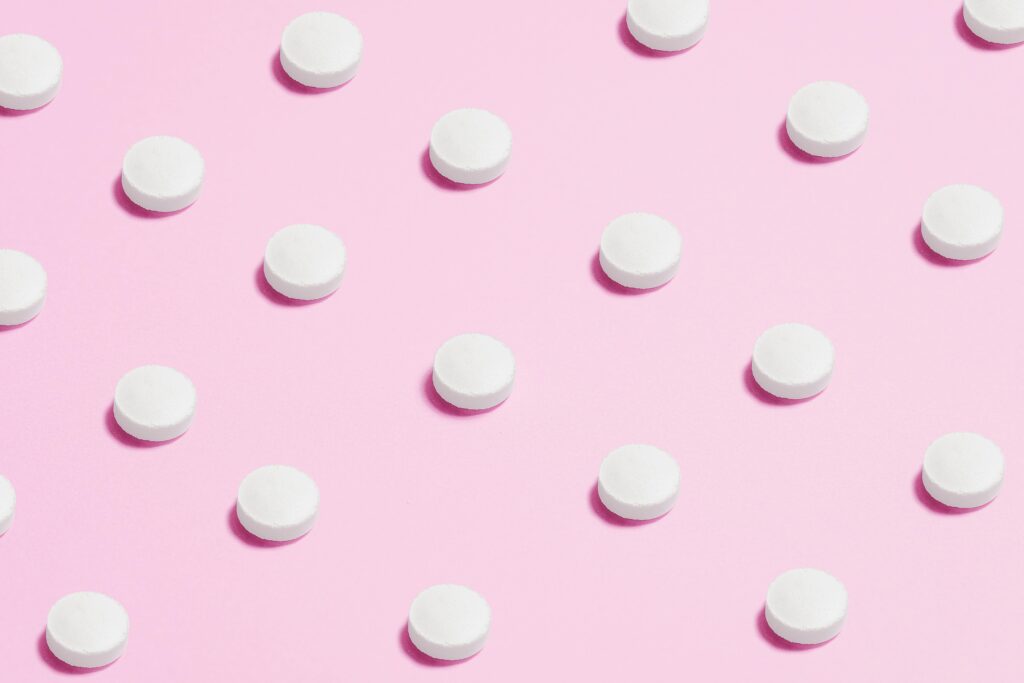 white round pills on a pink backdrop