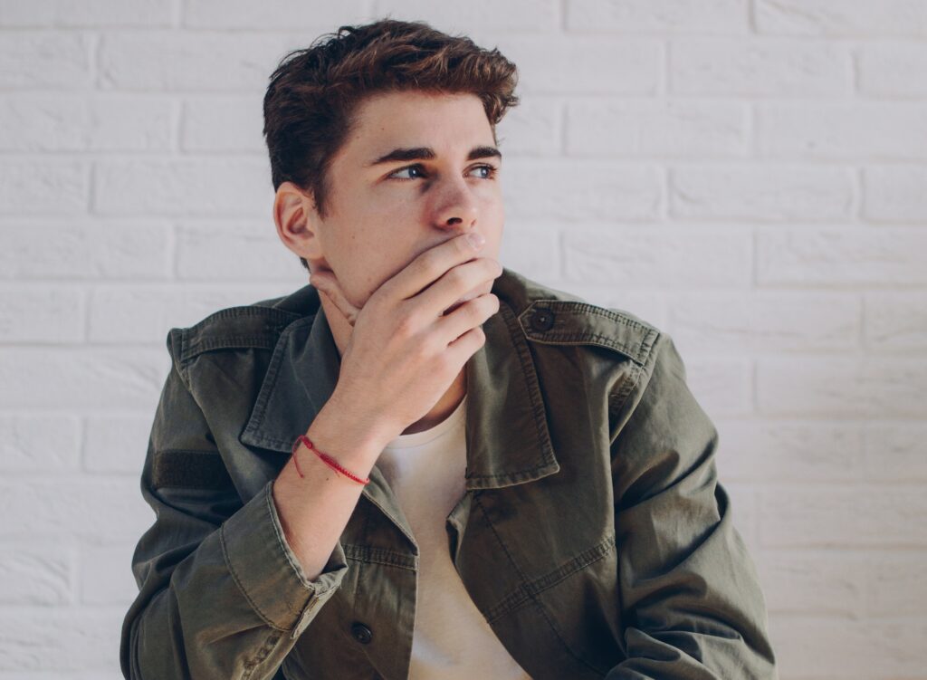 man covering his mouth and thinking